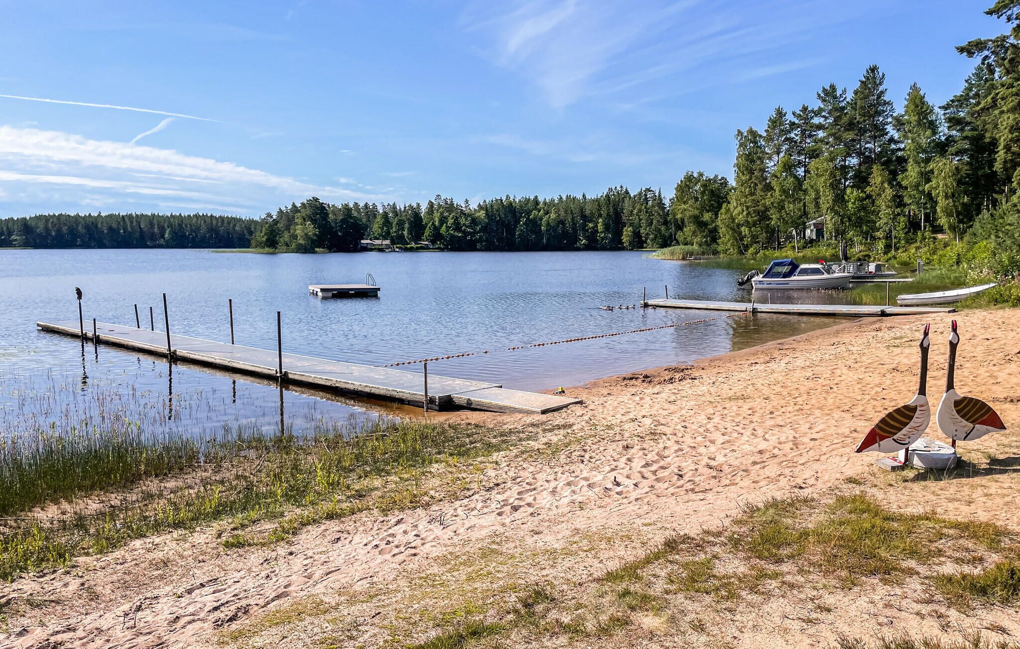 A lakeside beach with a dock, a boat, and a pier.
