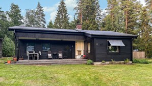Een zwarte chalet met een overdekte veranda, een schoorsteen en het nummer '22' op de zijkant.