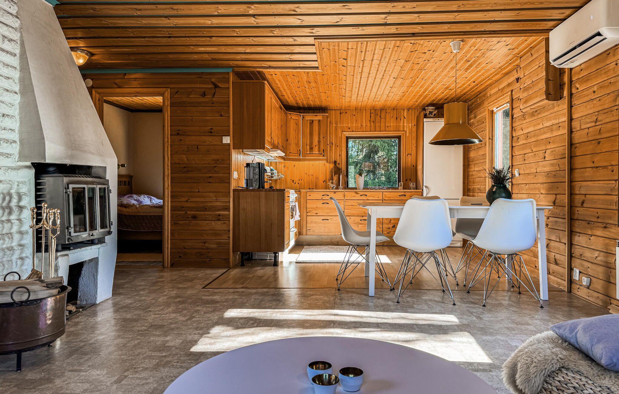 A cozy cabin interior with a dining area, kitchen, and a fireplace.