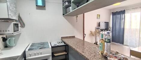 A compact kitchen with a microwave, stove, and countertop.