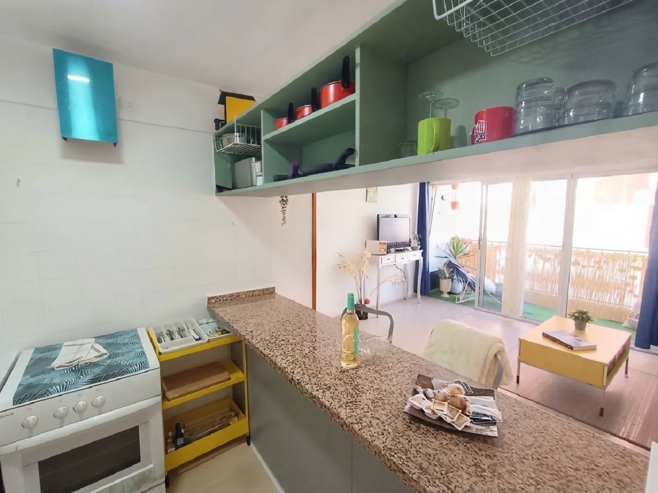 Una cocina con estufa a gas, una encimera y un comedor con mesa y sillas.