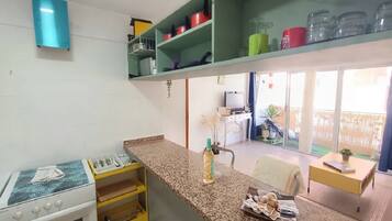 Una cocina con estufa a gas, una encimera y un comedor con mesa y sillas.