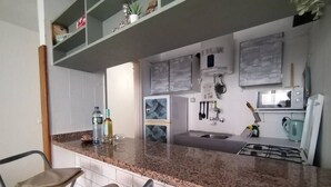 Uma cozinha com bancadas de granito, armários brancos, fogão embutido e micro-ondas.