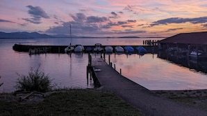 Roligt havneområde med fortøjede både, en bro og fjerne bjerge.