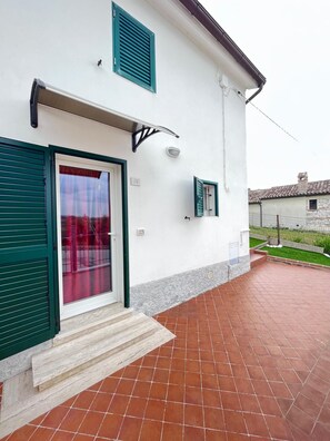 A white building with green shutters, a tiled patio, and a small staircase leading to the entrance. - Bilo Maria Grazia - delightful app.to with air condiizonata (Numana)
