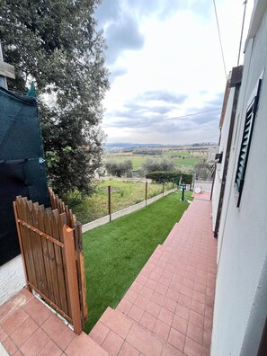 A narrow pathway leading to a grassy area with a wooden fence and a view of distant fields. - Bilo Maria Grazia - delightful app.to with air condiizonata (Numana)