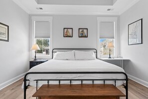 Quarto com cama, mesas de cabeceira, luminárias e obras de arte nas paredes.