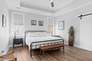 Una camera da letto con un letto, comodini, una panca, una ventola a soffitto e una testiera in legno.