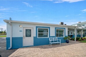 A building with a white door and windows, a bench, and a number '101' on the side. - Waterfront Condo | Heated Pool, Fishing Dock, Boat Slips & Walk to Beach (Treasure Island)