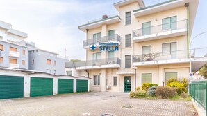 Un immeuble résidentiel à plusieurs étages, sur lequel on peut voir une enseigne indiquant « Immobiliare STELLA », ce qui signifie qu’il propose des services immobiliers.