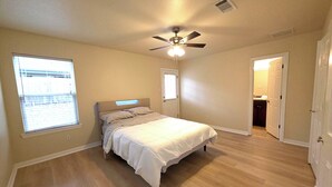 A bedroom with a bed, a ceiling fan, a window, and an open door leading to a bathroom. - Spacious 3BR Near AT&T Stadium-Global Life Field-Texas Live!-FIFA WorldCup2026 (Arlington)