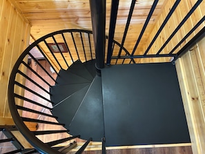 A spiral staircase with a black handrail and wooden walls. - Terrific 3-bedroom cabin with AC in cozy Fish Camp (Fish Camp)