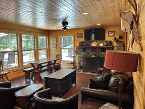 A wooden interior with a fireplace, a television, and a dining area. - Terrific 3-bedroom cabin with AC in cozy Fish Camp (Fish Camp)