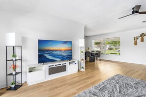 Ein modernes Wohnzimmer mit Flachbildfernseher, weißem Unterhaltungsschrank und einem grauen Teppich.