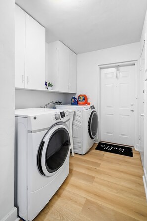 A laundry area with a washing machine, dryer, and cabinets.