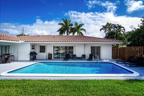 Ein Haus mit Swimmingpool, einer Terrasse mit Stühlen und einem umzäunten Garten.