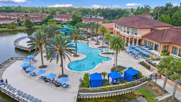 A resort with a central swimming pool, lounge areas with umbrellas, and a dock by the water. - Disney, Resort Style, 4 BDRM, Sleeps 8, 3 Bath (Kissimmee)