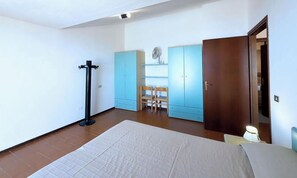 Ein Schlafzimmer mit Bett, Kleiderschrank, Stuhl und Schreibtisch.