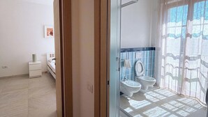 Bagno con porta in vetro, bidet, WC e zona doccia.
