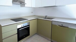 Una cucina compatta con forno a incasso, lavastoviglie e lavello.