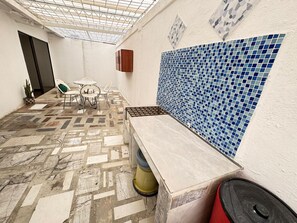 Una habitación con piso estampado, pared de azulejos, un banco y una puerta.