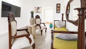 A room with a bed, two chairs, a TV, and artwork on the walls. - CASA LUCY ALOJAMIENTOS (Palmira)