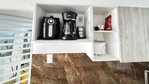 A kitchen with a coffee maker, a toaster, and a bag of snacks on the shelf. - CASA LUCY ALOJAMIENTOS (Palmira)