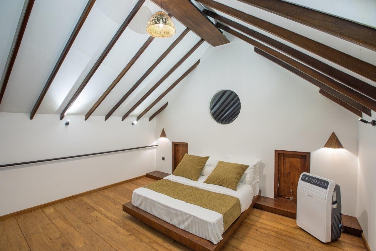 Une chambre avec un plafond en pente, un lit, un radiateur et un élément de décoration circulaire fixé au mur.