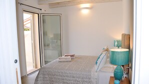 Een slaapkamer met een bed, een nachtkastje met lamp, een schuifdeur en uitzicht op het buiten.