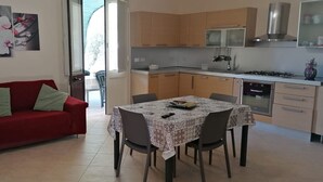 Ein kompakter Wohnraum mit Esstisch, einem roten Sofa und einer Küchenzeile.