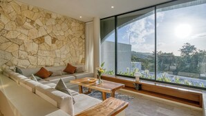 Uma sala de estar moderna com parede de pedra, uma janela ampla, um sofá e uma mesa de centro de madeira.