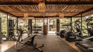 A gym with exercise equipment, a rack of dumbbells, and a large window. - Siwa Jungle-Luxury 2BR Retreat with Private Rooftop, Deep Pool & BBQ (Tulum)
