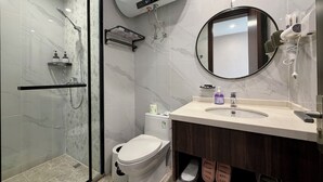 Moderni kylpyhuone, jossa on lasiseinällä varustettu suihku, wc, peilillä varustettu pesuallas ja pyyhekoukku.