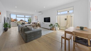 A modern living room with a sofa, a TV, and a dining area with a table and chairs. - Sunset Hideaway in Marino (Marino)