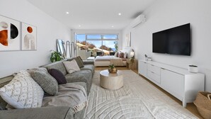 A modern living room with a sofa, a coffee table, and a TV. - Sunset Hideaway in Marino (Marino)