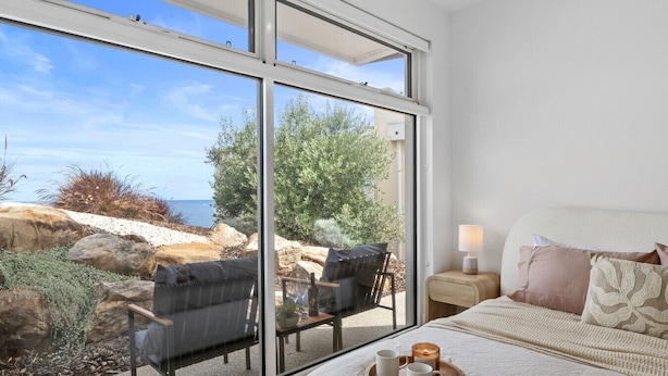 A bedroom with a large window, a bed with pillows, a bedside table with a lamp, and a tray with two mugs. - Sunset Hideaway in Marino (Marino)