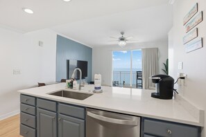 A modern kitchen with a large island, a coffee maker, and a view to the outside. - Splash Resort, 16th floor, Oceanfront, 1BR Sleeps 6, Lazy River & Water Park (Panama City Beach)