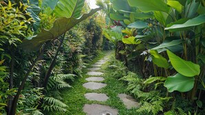 A stone pathway surrounded by lush greenery and large tropical plants. - DENAYA UBUD VILLA (Ubud)