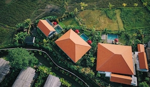 Vista aérea de um resort com vários edifícios, piscina e vegetação exuberante.