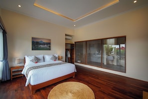 Quarto com cama, mesas de cabeceira, um quadro, guarda-roupa e uma janela grande.