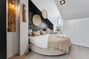 Een moderne slaapkamer met een rond bed, een wandlamp en een groot raam.