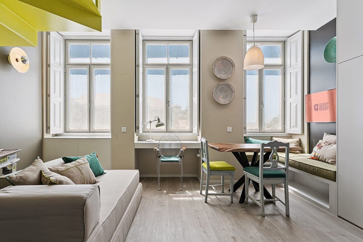 Ein modernes, gut beleuchtetes Zimmer mit großem Fenster, Essbereich und gemütlichem Sitzbereich.