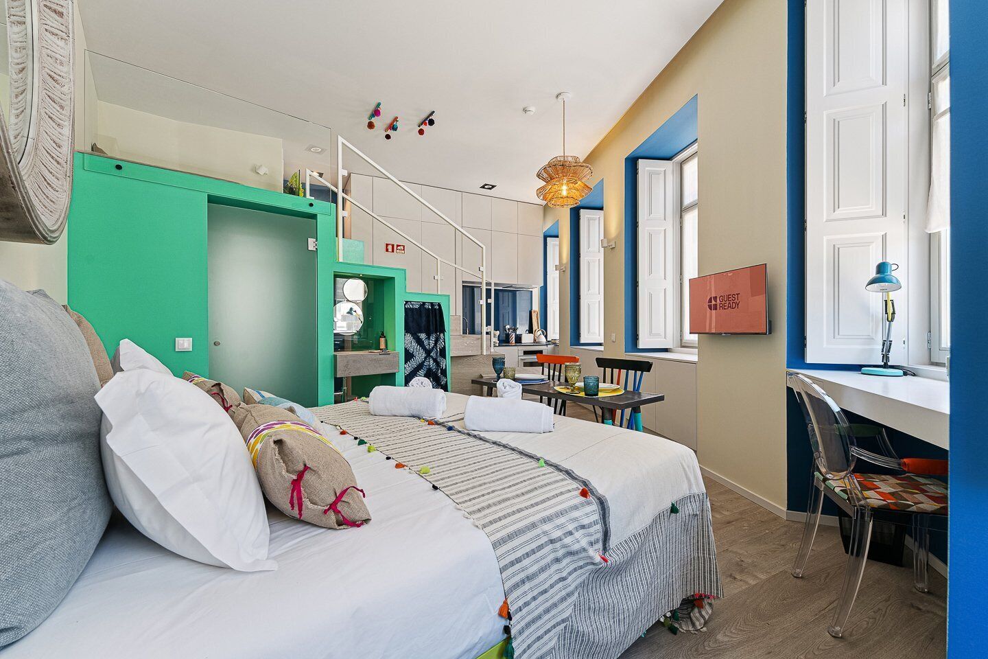 A modern hotel room with a bed, a desk, and a window.