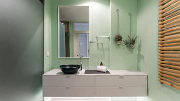 Un bagno con un ampio specchio, un lavabo nero, un asciugamano e una parete rivestita in listelli di legno.