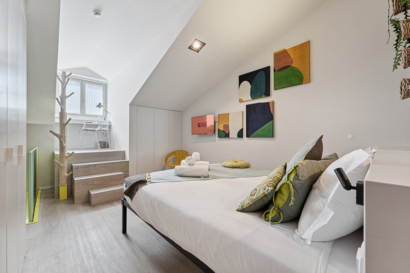 Un dormitorio moderno con cama, obras de arte y una escalera.