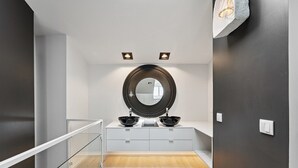 A modern bathroom with a large mirror, two black vessel sinks, and a glass railing. - Guestready - Amma Braga Apartments (Braga)