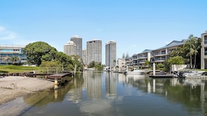 A marina with boats docked, a river, and high-rise buildings in the background. - Oatland 26 Esplanade Coastal Retreat (Runaway Bay)