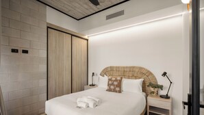 A modern hotel room with a large bed, wooden headboard, bedside tables with lamps, a potted plant, and a built-in wardrobe. - Oatland 26 Esplanade Coastal Retreat (Runaway Bay)