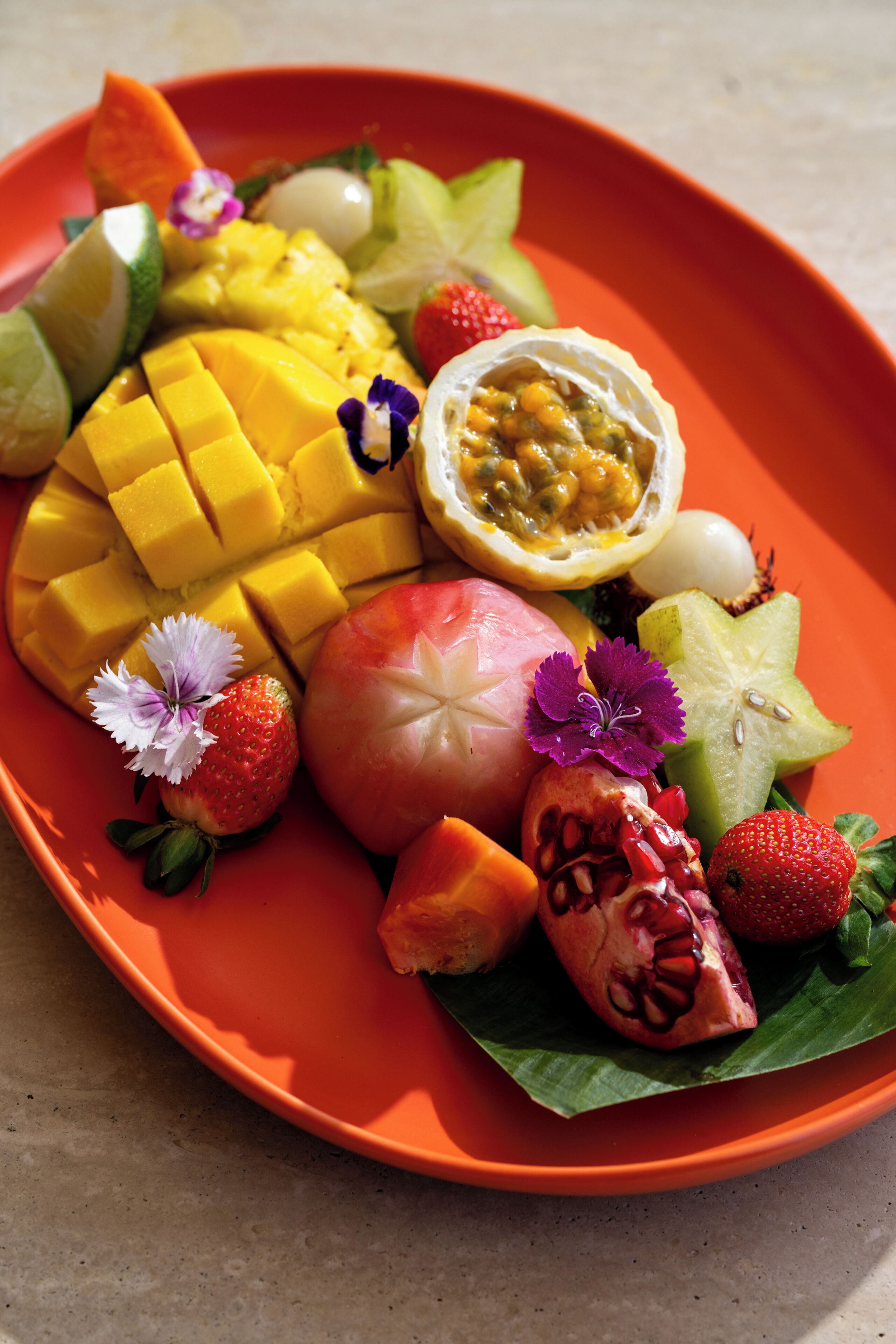 A plate of assorted fruits including mango, apple, and strawberry.