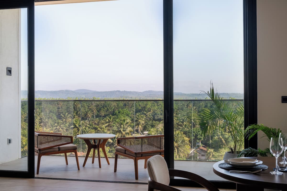 Un espace repas comprenant une table et des chaises, une vue sur un paysage verdoyant et une grande fenêtre.